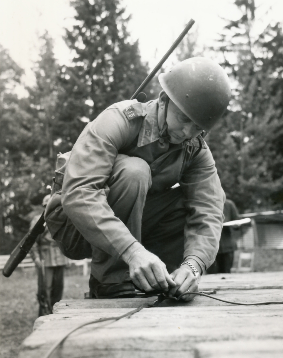 Rikshemvärnstävlingen 1967, sid 14 och 15

Min- och sprängtjänst.
Gruppen förbereder sprängning av en träbro med stridsvagnsminor. Minorna tänds med Sprängdeg och Pentylstubin.

Bild 1. Lag 105, TV Karlstad utför en korrekt 90-graders skarv på ringledning av Pentylstubin.

Bild 2. Lag 13, Hallabro, Fo 15. Gunnar Augustson och Per Pettersson.

Bild 3 och 4. Från samma stn.