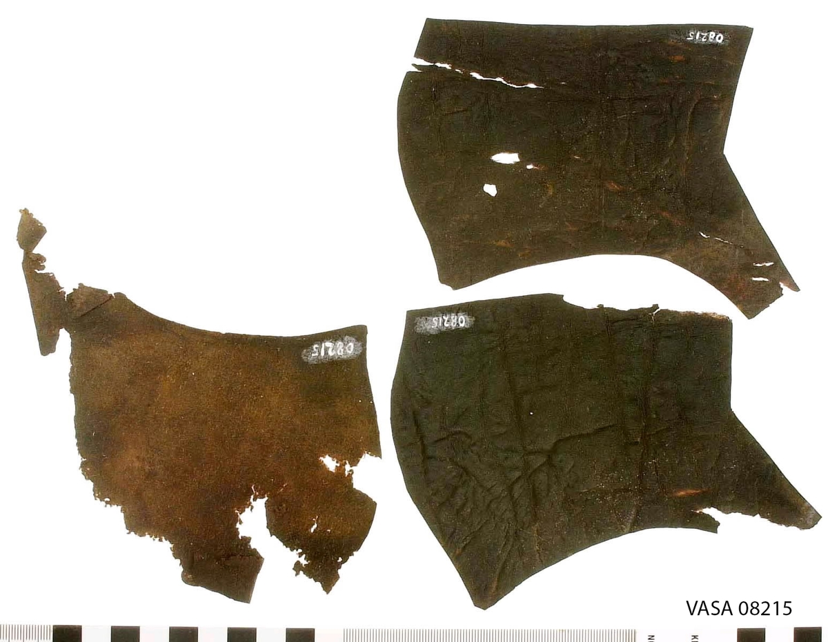 Dokumentation 1996:
Ovanläder samt sidostycken till skor. Totalt tio bitar. Tre stycken ovanläder varav ett fragmentariskt, sex stycken sidostycken med slejf, varav två fragmentariska. tre av sidostyckena är troligen avsedda för vänster sida av en sko och tre för höger. Ett mindre fragment, eventuell till en slejf.

Dokumentation 2022:
Tre par ovanläder till slutna skor. Framstycken och bakkappor. Tillverkade i läder, eventuellt hjortdjursskinn. Inga dekorationer. Det finns tecken på delaminering. Ovanlädren har skurits ut, men aldrig satts samman till skor. 
För mer information, se Uppritning under Länkade filer.

Text in english:
These 3 pairs of close shoe uppers were cut out but never made. Consisting of  quarters and vamps made of  moose (?) leather, with no decorative features. There is the presence of delamination.
For more information, go to Länkade filer: Uppritning