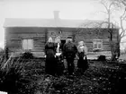 FAMILJ FRAMFÖR ETT BOSTADSHUS I LIGGANDE TIMMER.