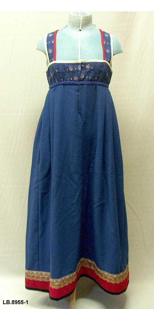 Uppluten sydd av blomstrete tøy og med perler bak. Kanta med ull og bomull. Pynta med agramaner i gull og sylv. Band til pynt, ingen broderi. 