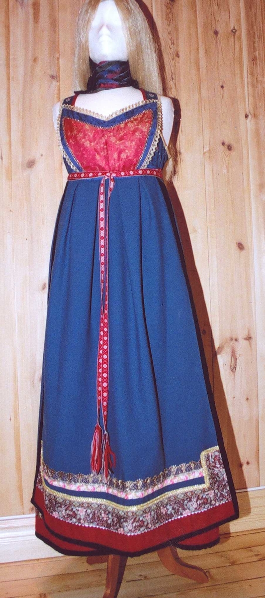 Uppluten sydd av blomstrete tøy og har perler bak. Kanta med ull og bomull. Bringekluten kan brukast på begge sider, raud på den eine, blå og lys gul på den andre. Forkleet kan og brukast på begge sider, blått på eine sida, lyst på den andre. Beltet skal brettast ned, slik at det framleis viser rettsida ut, når forkleet blir bruka på den blå sida. Forkleet er kanta med blått fløyelsband. Forkle, stakk og bringeklut er pynta med agramaner i gull og sylv. Band til pynt, ingen broderi. Drakta kan brukast i ulike samanhengar. Høgtidskledd med raud bringeklut. Med kvitt forkle er det eit endå meir høgtidsprega. Dersom ein i tillegg har la og belteklutar så er det brurestakk. Brukar ein lærbelte, er det meir kvardagplagg. Drakta kan varierast med forskjellige skjorter, sylv, plagg, og kan passe til mange typar bruk. Med den lyse sida av bringekluten fram er det meir kjøkkenfargr og meir sommarleg. Utan bringeklut kan ein bruke silkeplagg i bringa. Med  mindre pynt vert han tøffare, ein kan nesten bruke T-skjorte i staden for bunadsskjorte. 