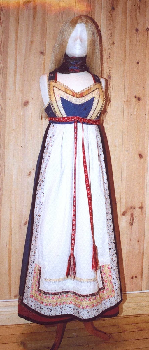 Uppluten sydd av blomstrete tøy og har perler bak. Kanta med ull og bomull. Bringekluten kan brukast på begge sider, raud på den eine, blå og lys gul på den andre. Forkleet kan og brukast på begge sider, blått på eine sida, lyst på den andre. Beltet skal brettast ned, slik at det framleis viser rettsida ut, når forkleet blir bruka på den blå sida. Forkleet er kanta med blått fløyelsband. Forkle, stakk og bringeklut er pynta med agramaner i gull og sylv. Band til pynt, ingen broderi. Drakta kan brukast i ulike samanhengar. Høgtidskledd med raud bringeklut. Med kvitt forkle er det eit endå meir høgtidsprega. Dersom ein i tillegg har la og belteklutar så er det brurestakk. Brukar ein lærbelte, er det meir kvardagplagg. Drakta kan varierast med forskjellige skjorter, sylv, plagg, og kan passe til mange typar bruk. Med den lyse sida av bringekluten fram er det meir kjøkkenfargr og meir sommarleg. Utan bringeklut kan ein bruke silkeplagg i bringa. Med  mindre pynt vert han tøffare, ein kan nesten bruke T-skjorte i staden for bunadsskjorte. 