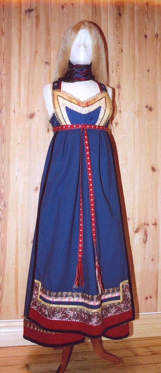 Uppluten sydd av blomstrete tøy og har perler bak. Kanta med ull og bomull. Bringekluten kan brukast på begge sider, raud på den eine, blå og lys gul på den andre. Forkleet kan og brukast på begge sider, blått på eine sida, lyst på den andre. Beltet skal brettast ned, slik at det framleis viser rettsida ut, når forkleet blir bruka på den blå sida. Forkleet er kanta med blått fløyelsband. Forkle, stakk og bringeklut er pynta med agramaner i gull og sylv. Band til pynt, ingen broderi. Drakta kan brukast i ulike samanhengar. Høgtidskledd med raud bringeklut. Med kvitt forkle er det eit endå meir høgtidsprega. Dersom ein i tillegg har la og belteklutar så er det brurestakk. Brukar ein lærbelte, er det meir kvardagplagg. Drakta kan varierast med forskjellige skjorter, sylv, plagg, og kan passe til mange typar bruk. Med den lyse sida av bringekluten fram er det meir kjøkkenfargr og meir sommarleg. Utan bringeklut kan ein bruke silkeplagg i bringa. Med  mindre pynt vert han tøffare, ein kan nesten bruke T-skjorte i staden for bunadsskjorte. 