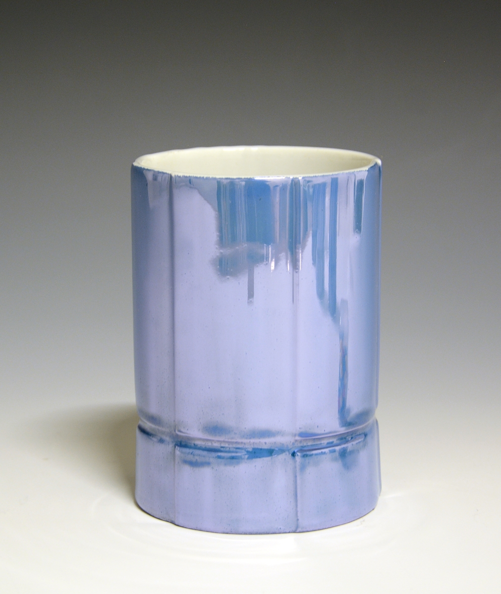 Vase og telysholder av porselen. Fungerer som lysestake den ene veien og vase den andre veien. Sylinderformet med en inntrapping i overgangen mellom vase og telysholder. Hvit glasur. Dekorert med blåfarget heldekkende dekor. Ustemplet
Design: Grete Rønning.