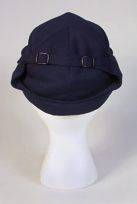 Herrmössa, skärmmössa (sport). Kilskuren kulle. Uppvikt vid sidorna. 
   Mått: Runt kullen 490 mm. Kullens höjd 170 mm. 
   Storlek: 55.