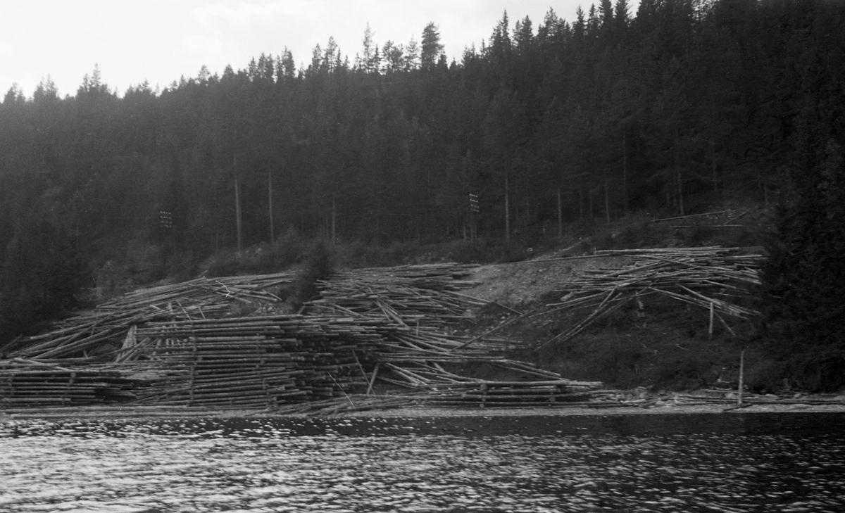 Tømmervelte som ifølge innskrift under en albumkopi av fotografiet skal ha ligget sør for Fjerdingshammeren ved Storsjøen i Rendalen våren 1947.  Tømmeret er delvis floret, til dels bare veltet av sledene fra den ovenforliggende bygdevegen ned den bratte strandskråningen.  Den minste av de florete stablene (til høyre i bildet) består bare av fire lag, den høyeste (i midten) består av om lag tjue lag med mellomliggende tverrstokker.  Det virket som bare er veltet av sledene ligger nokså hulter til bulter, dels bak den største velta, dels nedover i skråningen og dels oppunder vegkanten.  Dette virket må det ha vært nokså arbeidskrevende å få slått på sjøen.  Bakkekammen i bakgrunnen har forholdsvis tett barskog. 