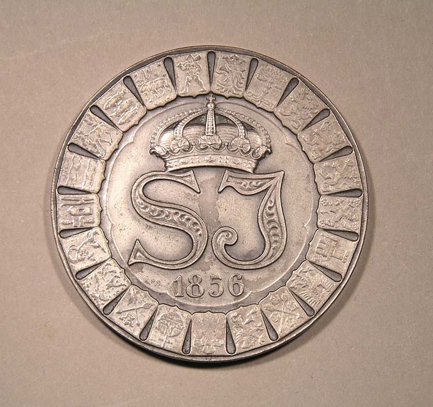 Minnesmynt i silver från Statens Järnvägars 75 års jubileum 1931.
På myntets ena sida syns SJ:s monogram i en cirkel av länsemblem, under detta årtalet 1856.
På andra sidan står årtalen 1906 och 1931, och mellan dessa avbildas ett ånglok, samt en flygande gudafigur med mantel som drar (?) ett ellok.