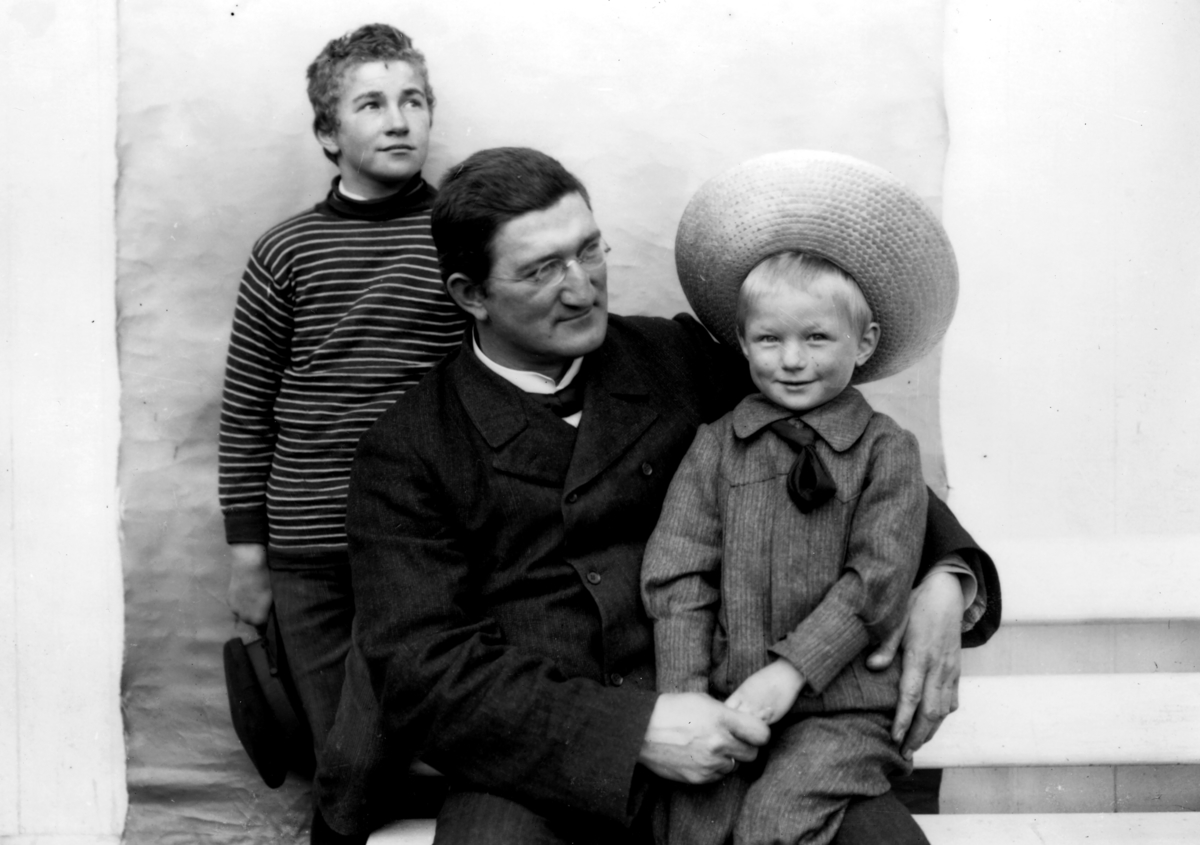 Doktor Otto Mejlænder med barn.
Bak Otto Mejlænder er førstefødte sønn (med avdøde kone Elise Lydia født Oftedal). Født 1892 med navnet Otto som faren. Gutten på fanget er antakelig sønn Odd Egil født 1902. Så foto må være fra ca 1905.
