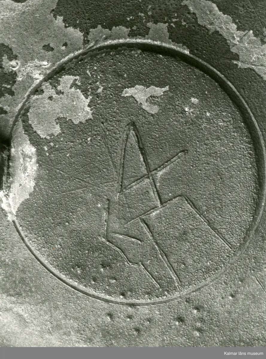 KLM 46428 Kanna av tenn. Bukig form. Hankkärl, försedd med lock och handtag, vidgad botten neråt. I botten, invändigt en medalj med korsfästelsebild. Medaljens kant försedd med pärlring. Ägarmärke/bomärke på lockets och bottens utsidor. Handtaget ornerat med drakmotiv och bladslinga, tumgreppet saknar ett av ekollonen. Kannan skadades svårt vid upphittandet, genomgående sprickor på många ställen.