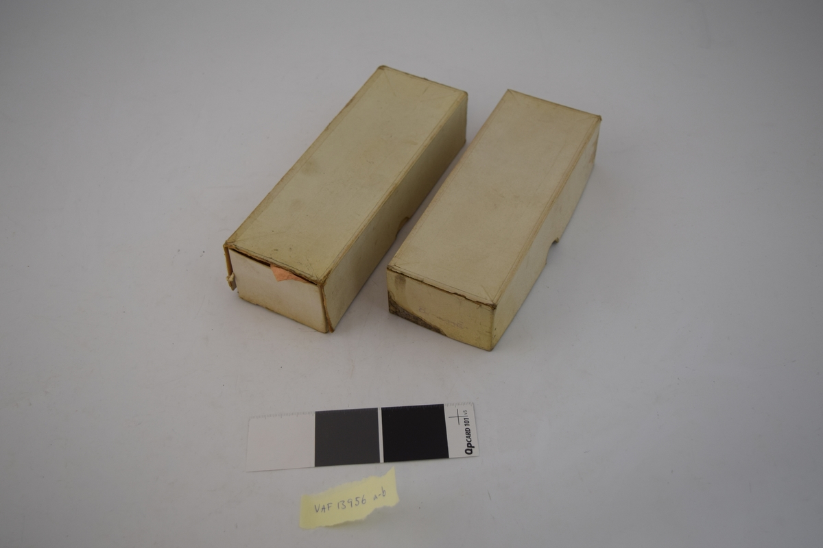 To stk. papiresker med bunn og lokk. Den ene inneholder seks trådsneller med brun bomullstråd produsert i Stor Britannia. Den andre esken inneholder diverse små metalldeler som knapper, spenner og lignende, trolig deler som har vært brukt på sko tidligere. Ingen etiketter eller påskrifter på eskene.