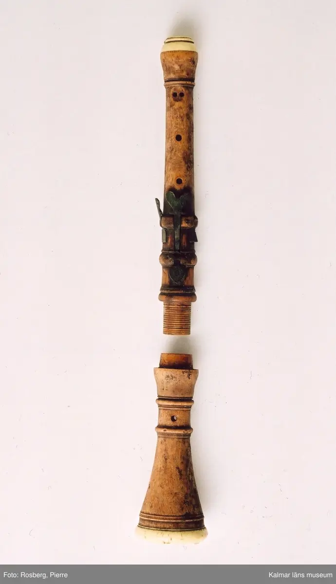 KLM 14811. Oboe, barockoboe. Av trä, metall och ben, eventuellt elfenben. Klaffar av metall, två fyrkantiga och en hjärtformad. Består av två delar, ej komplett, delar saknas. Försedd med Stålhammarska vapnet samt OFSH, majoren Otto Fredrik Stålhammars initialer. Tillverkarstämpel på båda delarna, text på språkband, otydlig text: H LVBBKE.