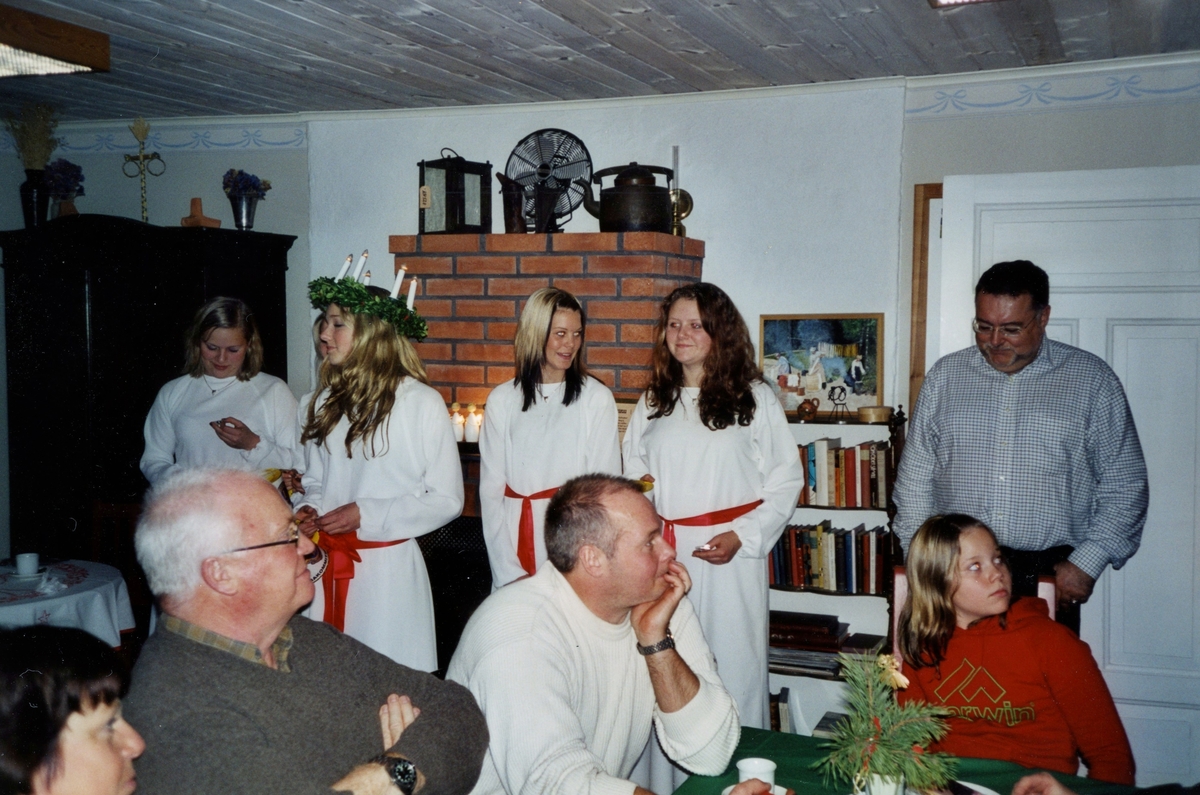 Julfest arrangerad av Hembygdsföreningen på Långåker 2004-12-15. Kållereds Lions luciatåg (namnuppgifter saknas) uppvaktar för besökare. Närmast från vänster: Annika Bjerrhede, Hans Lundén, Mats Lindström samt okänd flicka. Bakom henne står Staffan Bjerrhede.