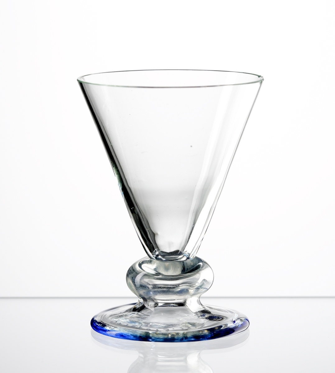 Likörglas.
Konstnär: Simon Gate.
Litet glas med v-form, stor kula innan bats och fot,
Stolpräfflad.
Sprängt, slipad kant.
Blåtonad degelfärg.
Sålt under varumärket Orrefors, tillverkat vid Sandviks Glasbruk.
Funktion: Likörglas