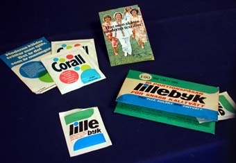 :1-5 Fyra stycken likadana förslutna påsar av vitt papper med tvättmedel inuti. På utsidan tryck i svart, grönt, blått och rött: "Lille byk. Snabb kalltvätt för ylle kulört och fintvätt" samt bruksanvisning på baksidan. "Vara med varufakta. AB Helios kemiskt tekniska fabriker Stockholm". Längd: 92 mm, bredd: 65 mm. Påsarna förvarade i förpackning av papp vikt som ett kuvert med fickor som håller påsarna på plats. Har från början innehållit 10 portionspåsar med tvättmedel. Tryck i samma färger och med samma text som på påsarna samt angivet "Riktpris": 1:90. Längd: 165 mm, bredd: 105 mm.
:6-9 Två stycken likadana förslutna påsar av vitt papper med tvättmedel inuti. På utsidan tryck i svart, rosa, blått och grönt: "Corall. Specialmedel för tvätt av moderna textilmaterial. Nyhet från Sunlight" samt bruksanvisning på baksidan. Längd: 105 mm, bredd: 90 mm. Påsarna förvarade i påse av papper vikt som ett kuvert. Tryck i samma färger och med samma text som på påsarna samt "Moderna kläder tvättar man själv. Det är det som är meningen. Var så god: Två provpåsar med Corall och en broschyr med tvättråd!" Längd: 150 mm, bredd: 105 mm. Tvåsidig informationsbroschyr med bruksanvisning av tvättmedlet och tvättråd gällande textilier. På framsidan foto med fyra damer i moderna kläder samt texten: "Hur man sköter moderna textilier". Längd: 145 mm, bredd: 90 mm.