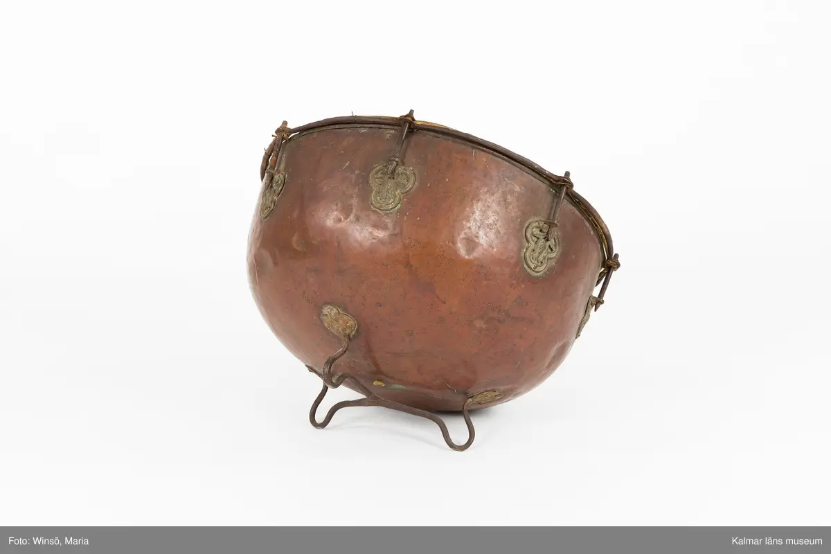 KLM 14939. Puka. Av koppar med beslag av järn och skinn på ovansidan. Står på tre korta ben formade som öglor. På utsidan skruvar och beslag formade som tulpaner. Försedd med Stålhammarska vapnet. Par med KLM 14940. Har eventuellt använts tillsammans med pukstockar KLM 14850-51.