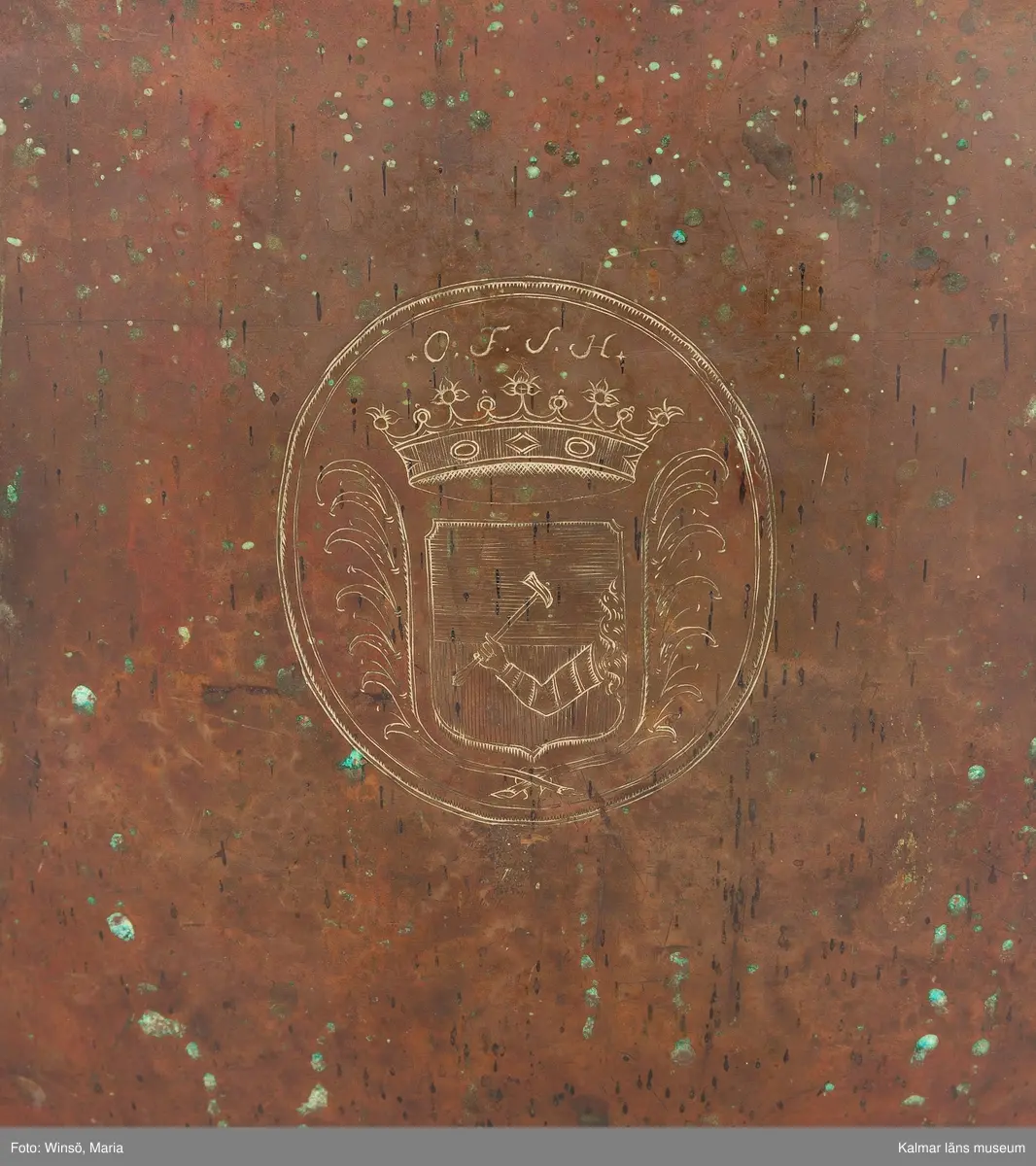 KLM 14939. Puka. Av koppar med beslag av järn och skinn på ovansidan. Står på tre korta ben formade som öglor. På utsidan skruvar och beslag formade som tulpaner. Försedd med Stålhammarska vapnet. Par med KLM 14940. Har eventuellt använts tillsammans med pukstockar KLM 14850-51.