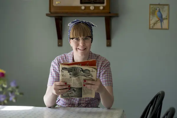 Husmora Bjørg leser ukeblad på 50-talls kjøkkenet