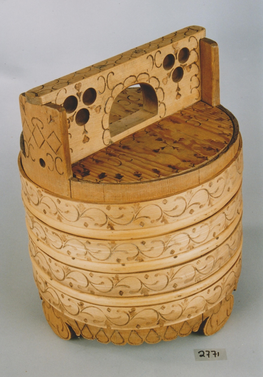 En dall av tre med trelokk. Den har fire brede trebånd og tre smale trebånd. De brede trebåndene har dekor i form av sviornamentikk. Møsnteret er spinkle ranker. Nederst på dallen er det skåret ut en tungekant som har svidd dråpemønster. Dallen står på tre bein som også har svidekor. Lokket har et firkantet håndtak. Både håndtak og lokk har sviornamentikk (rutemønster, halvsirkler og noe som minner om små blomster). På håndtaket er det skåret ut tre hull på hver side.