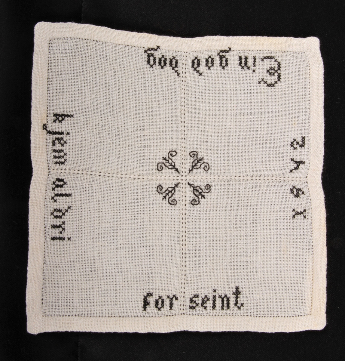 Natur bunn med svart dekor, brodert korsting, hullsøm og attersting. Border, tekst og blomster.