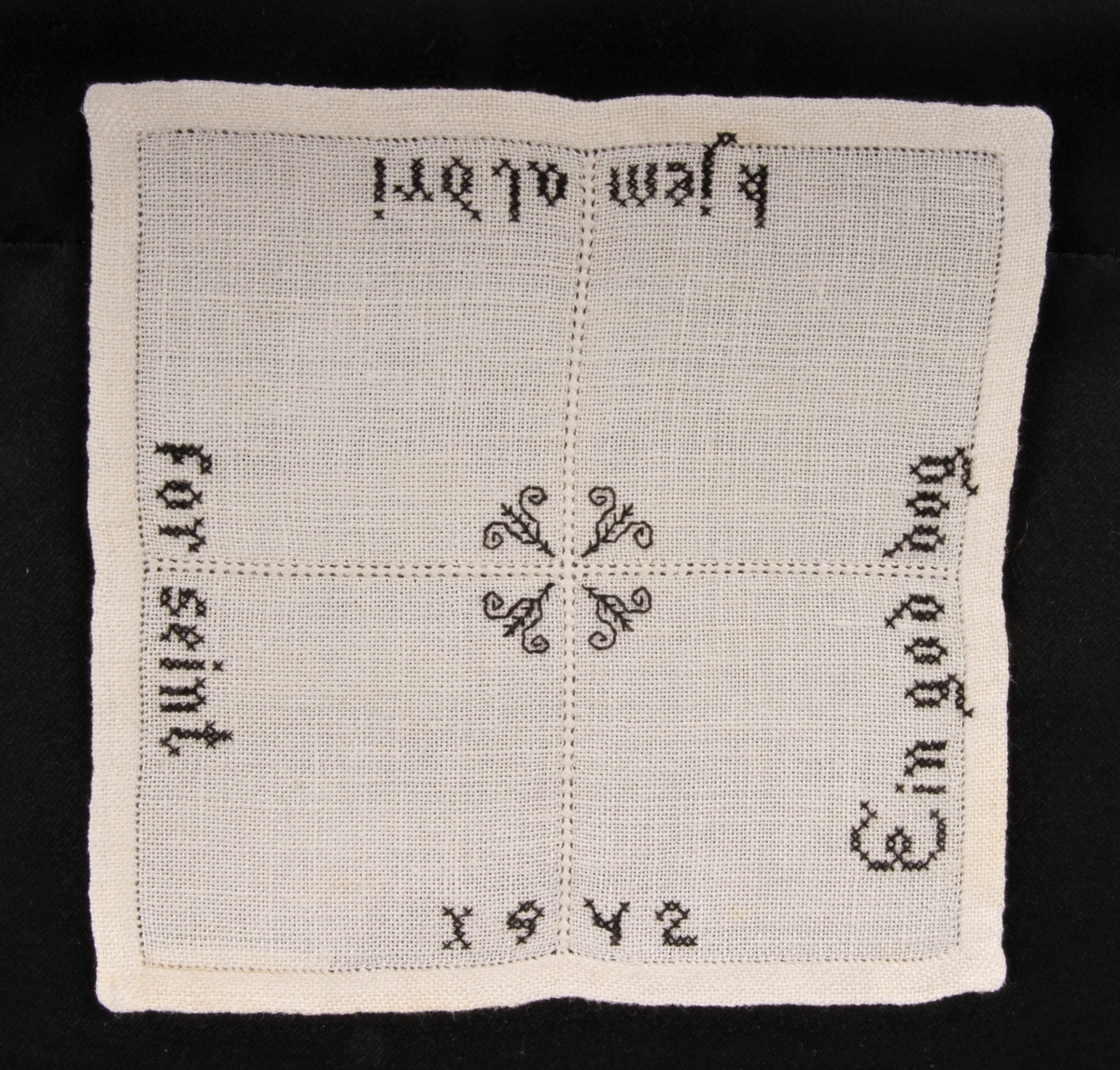 Natur bunn med svart dekor, brodert korsting, hullsøm og attersting. Border, tekst og blomster.