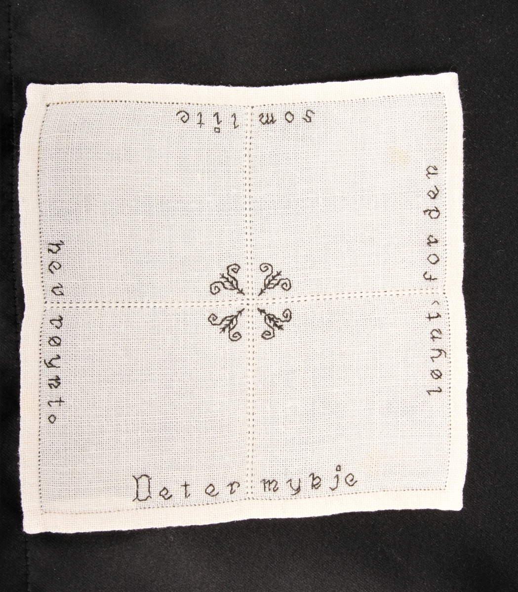 Natur bunn med svart dekor, brodert korsting, hullsøm og attersting. Border, tekst og blomster.