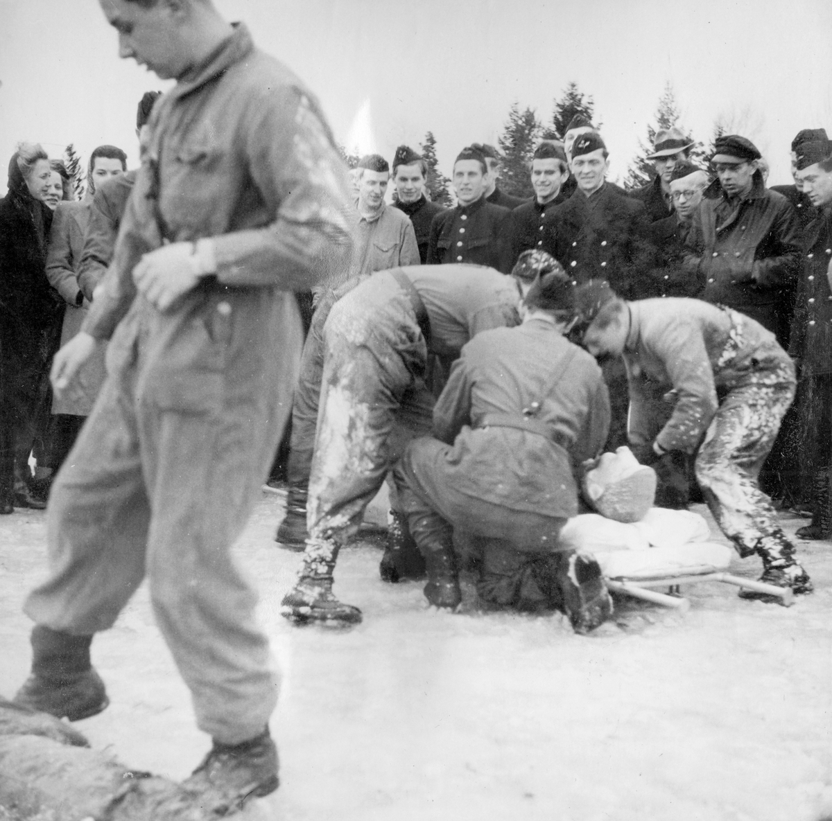 Soldater övar första hjälpen av skadad docka som räddats ur brinnande flygplansattrapp vid sjukvårdsövning på F 11 Södermanlands flygflottilj, 1945.

Vintertid.

Ur fotoalbum "Sjukvårdsskolan 15/1-15/3 1945" från F 11.