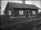 Torp med kvinna och barn på trappan, ca 1910.