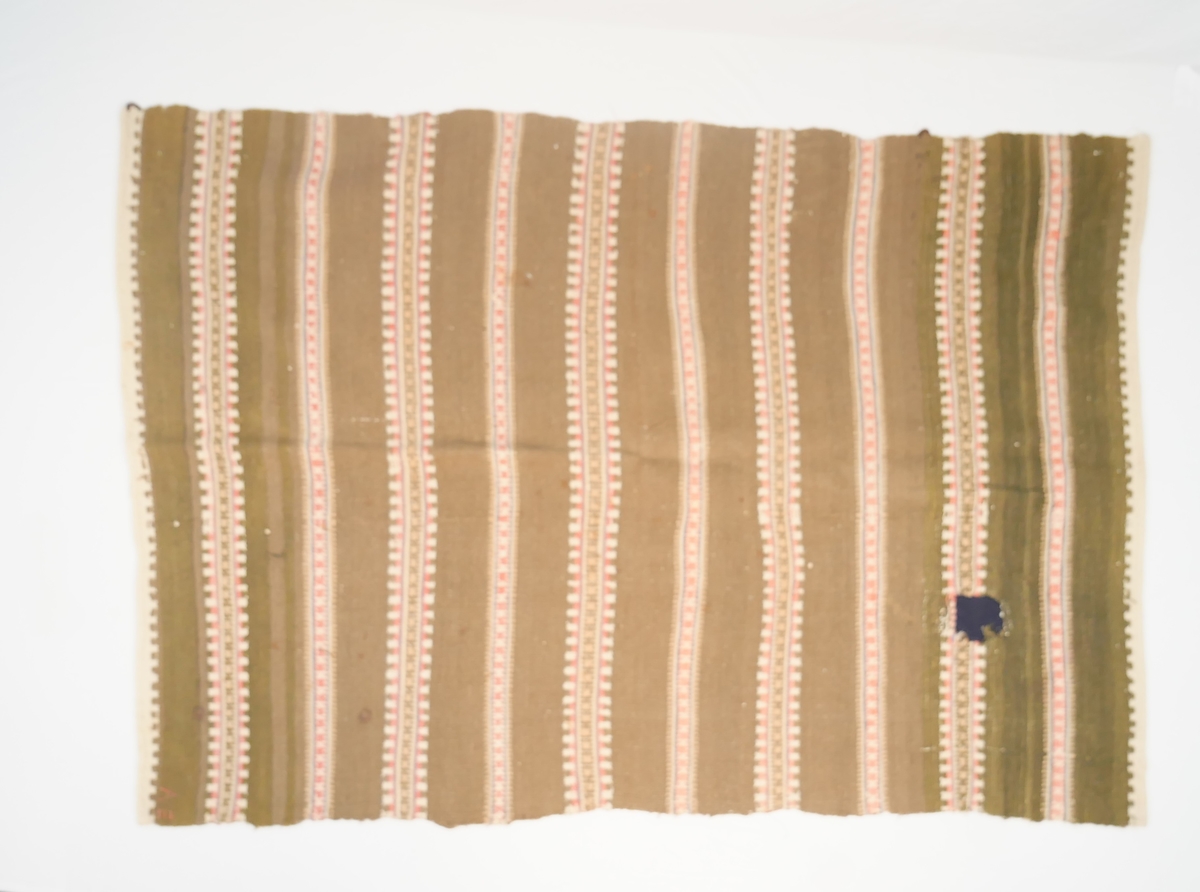 Teppet er vove i ei breidd, falda i endane. Fjølrøysåkle med to ulike mønsterrapportar.
