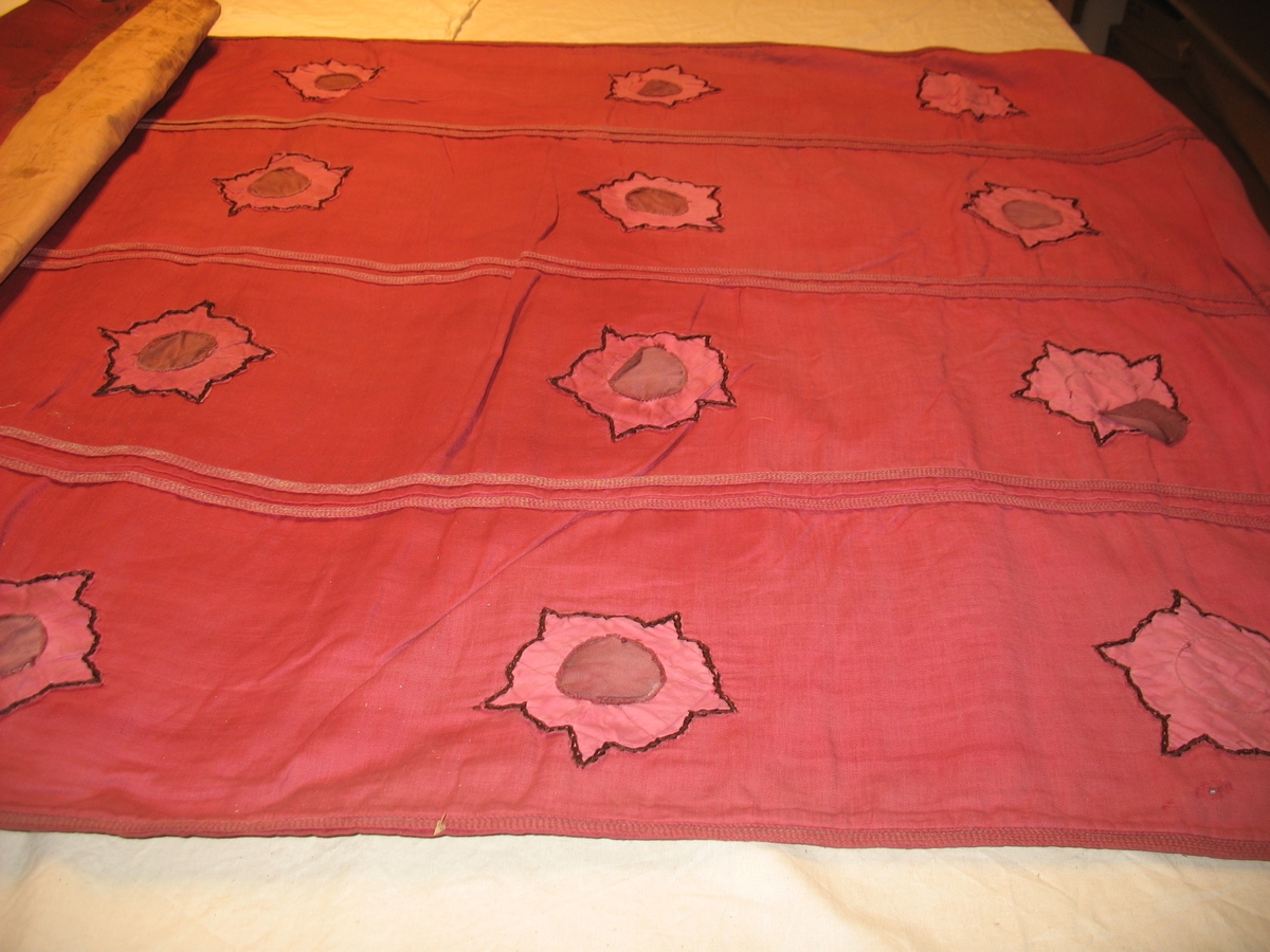 Øvre del: Olav Haraldsson med krone, kappe og øks, som står på en "underligger" formet som en drage med menneskeansikt. Nedre del: påsydde blomster