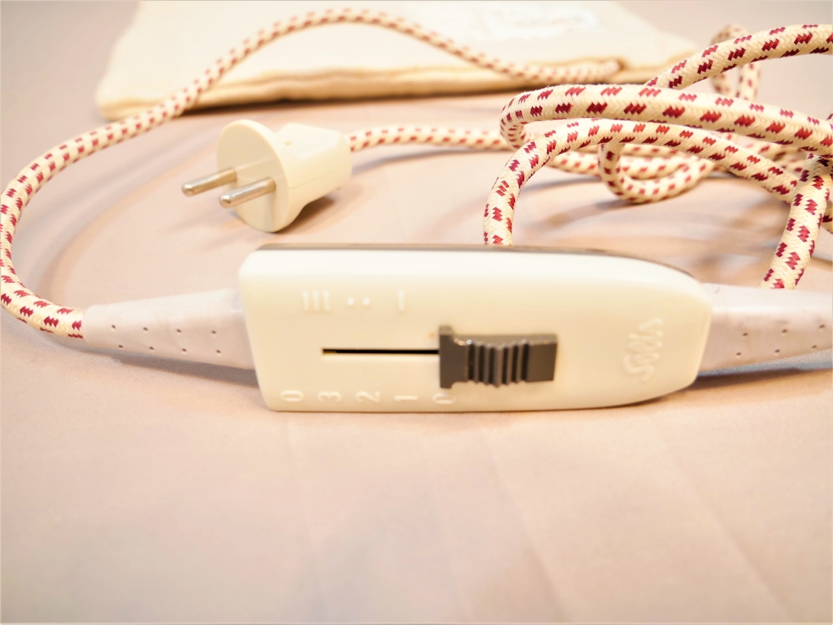 Flat pute med innsydd elektrisk kabel, ledning med brytar og støpsel.
Lerretstrekk utanpå.