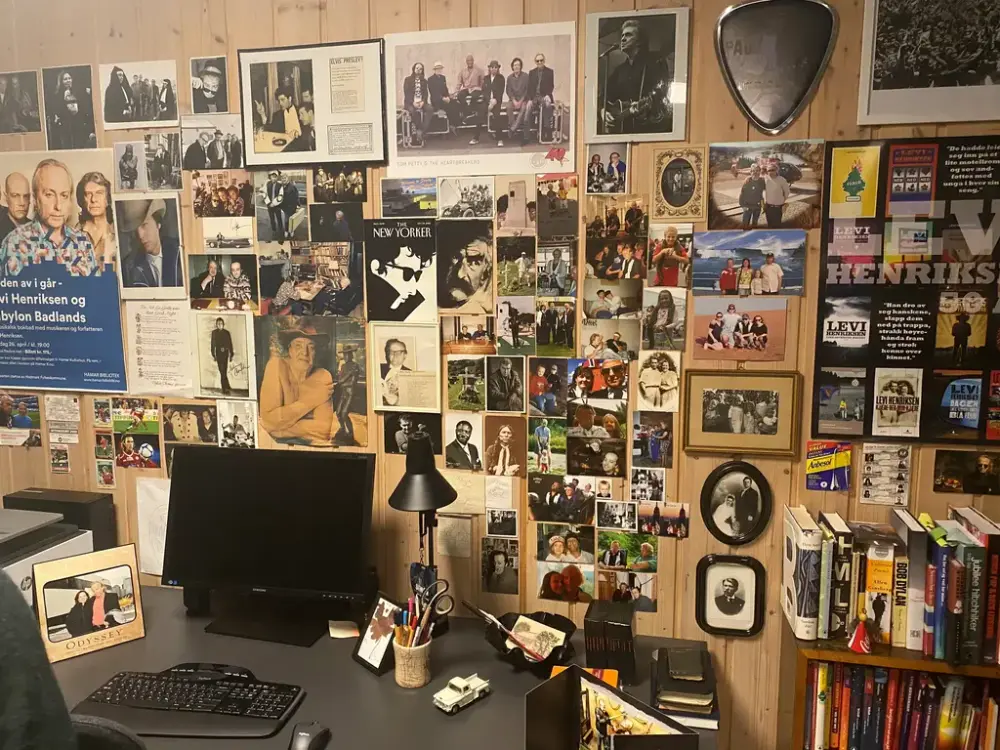Bilde av en vegg i skrivestua og Levis PC. Veggen er full av fotografier og bilder.