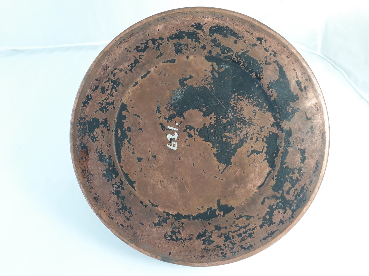 Kaffekjele i kobber med lokk. Sirkulær med innsnevring mot lokket og utvidelse mot en bredere fotkant. Hankfestet ved tuten og på motsatt side.