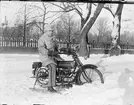 Man i uniform sitter på en motorcykel med skidor, Boden