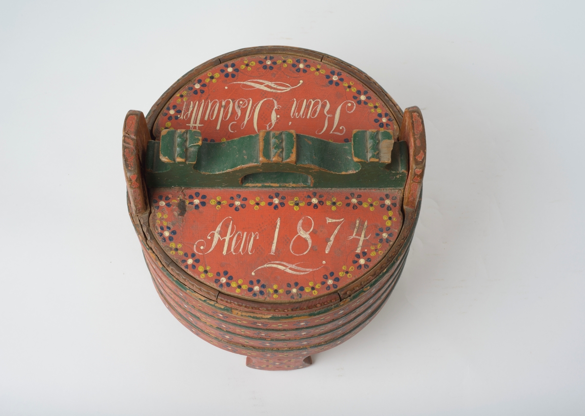 11 staver, tildels sterkt avrundet, holdt sammen med fire flate og fem avrundete gjørler. Tre staver forlenget til bein, dobbelt dyrefot, to staver forlenget til ører, gjennomhullet sirkulære hull. Botn felt inn i stavene, spår for lokket i stavene. Lokk, sirkulært hakk for øra. Felt inn handtak, buet, med tre kroner, halvsirkel hull for hand.