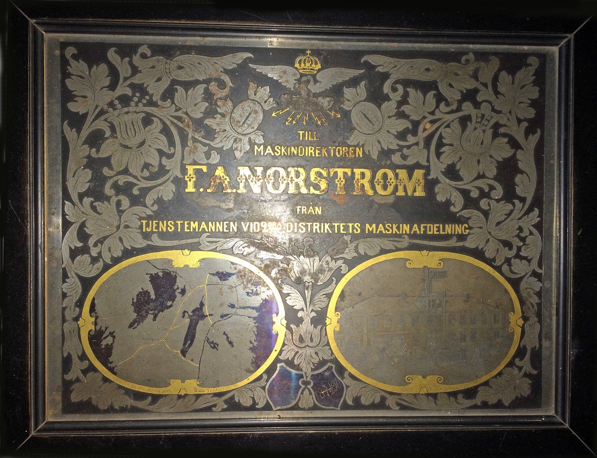 Mindre skåp med ett tillhörande bord eller sockel. Skåpet är gjort av svartbehandlat trä.

Skåpdelen är rektangulär med två luckor på framsidan. Luckornas framsidor och skåpets ovansida är dekorerade med infällda ståletsningar, delvis förgyllda och blånerade, i en form för intarsia.
På ovansidan står följande text i förgylld metall ovanför två ovaler med guldram:
"Till Maskindirektören F. A. Norström från Tjenstemännen vid 2dra distriktets Maskinafdelning". I den vänstra ovalen är avbildat en karta med texten "Statens Jernvägars 2dra Trafikdistrikt" under, och i den högra ovalen finns avbildat en byggnad med texten "Statens Jernvägars Verkstad och Förråd" under. Byggnaden är SJ:s verkstäder i Göteborg samt förråd byggda år 1864 och slopade 1929. Mellan de två ovalerna finns två sköldar med datumen 1/9 1858 och 31/12 1890, vilket är de år då Norström tjänstgjorde vid SJ.

Mitt på varje skåplucka finns en dörrspegel med förgyllt bladmönster runtom en oval inom vilka motiv är etsade i metall: En hjulsvarv i den vänstra ovalen och ett ånglok (SJ Kd 390) i den högra. Speglarna omges i sin tur av figurer och mönster av tunnt stål som är fastnitade på luckorna. Låsblecken har form av figurer som föreställer manliga sjöjungfrur med svärd och soldathatt med plym, samt drakar och löv.

Bordet som skåpet står på har två framben svarvade och karvade med dekorativa former. Mellan bakbenen en heltäckande skiva som skapar ett intryck av att bordet i stället för bakben har ett bakstycke. Mellan frambenen en tvärslå som i vardera ände har en svarvad och täljd trädekoration. På framsidan av sargen finns en dekoration av blommor och blad vars former framträder genom att trät är slipat.