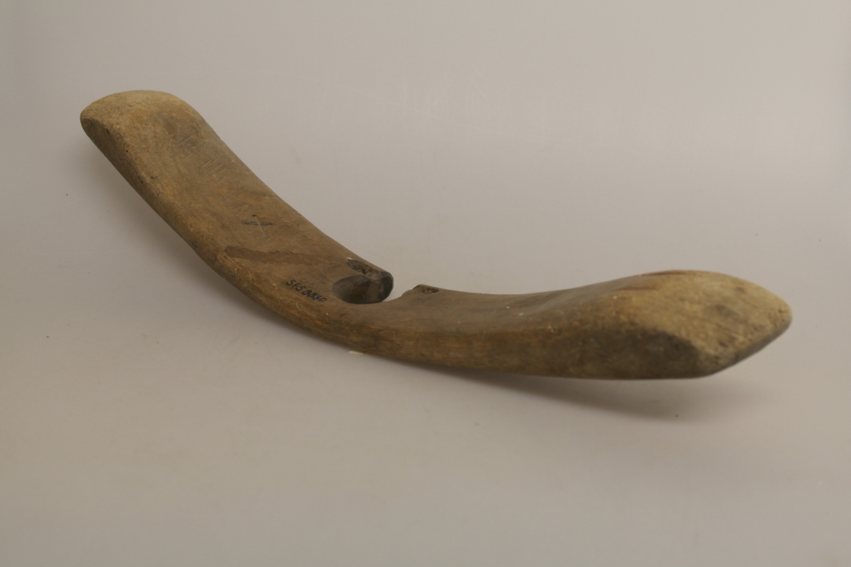 Sauestokk i tre. Stokken er buet og har en rund utsparing på midten samt to små hull på hver side av utsparingen. På den ene siden er det inngravert ett kryss samt et håndskrevet personnavn. En merkelapp med håndskrevet tekst har vært festet til stokken med hyssing. Stokken ble brukt for å hindre sau å hoppe over gjerde o.l. ved å feste den til sauens ben.