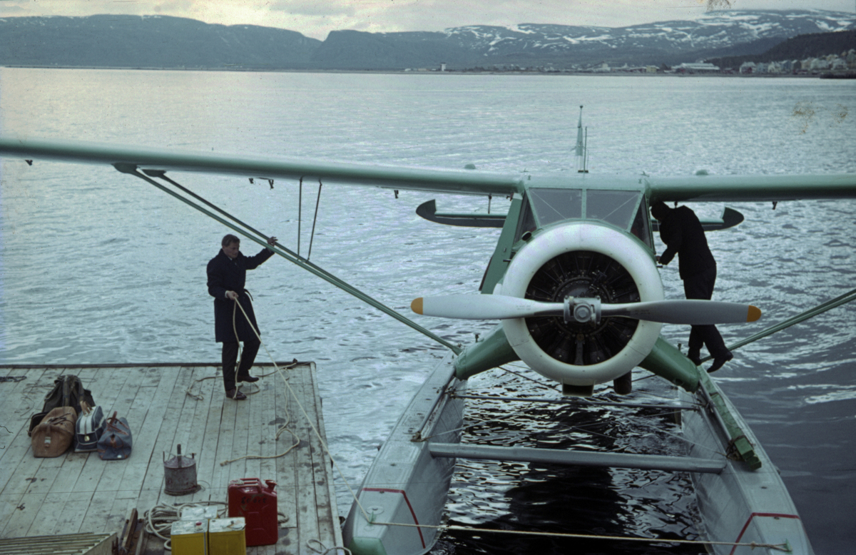 En Noorduyn Norseman er i ferd med å bli fortøyd ved en sjøflyhavn. På flytebrygga står bagasje og drivstoffkanner.