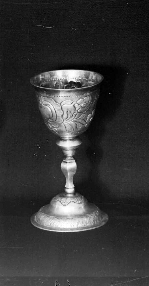 Beger av sølv. Begeret har stett og rund sokkel. På klokken er det to border med dekorative punslinger, mellom bordene er det drevet dekor av blomster. Siselert bølgedeker på sokkel.