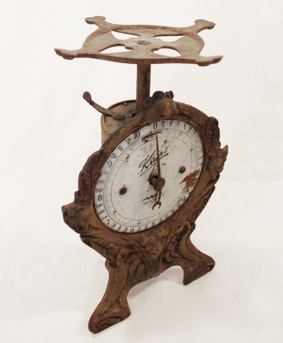 Fjærvekten går til 10 kg og er av merket Krups. Vekten er støpt i jern og blikkplater har blitt brukt på baksiden. 

Fra samlingen etter Ole Gjestvang. 