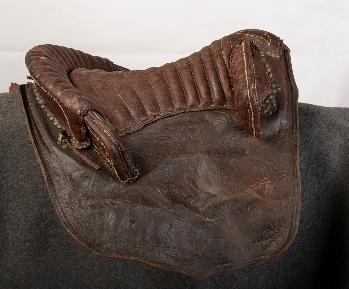 Lærtrukket sadel fra 1778. Initialene ONS brodert. Kapper med preget lær. 