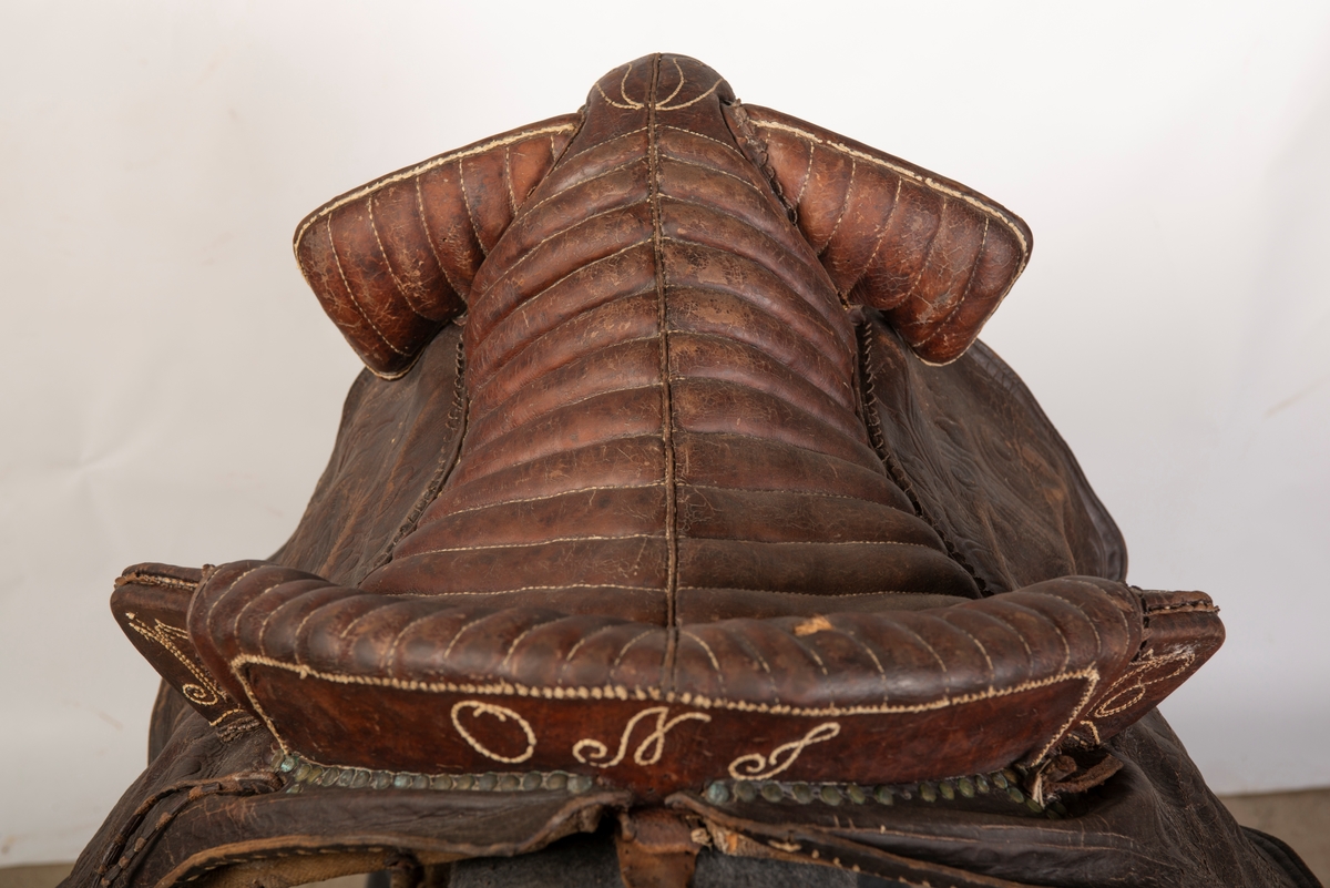 Lærtrukket sadel fra 1778. Initialene ONS brodert. Kapper med preget lær. 