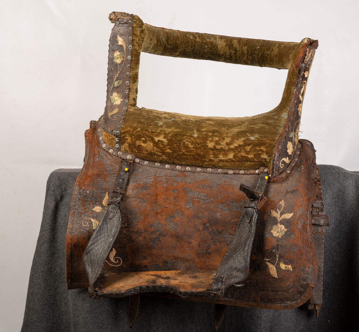 Brodert lær. Grønn mønstret  fløyel i setet og på armlene. Messinghode på fremre del av rygglenet. Initialene KDS og årstallet1773 brodert på. Løs narv på kappene, redrot.