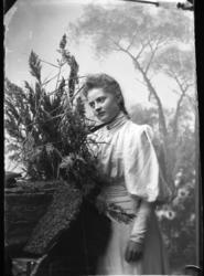 Porträtt av fröken Ester Grönberg. Hon står lite drömmande l