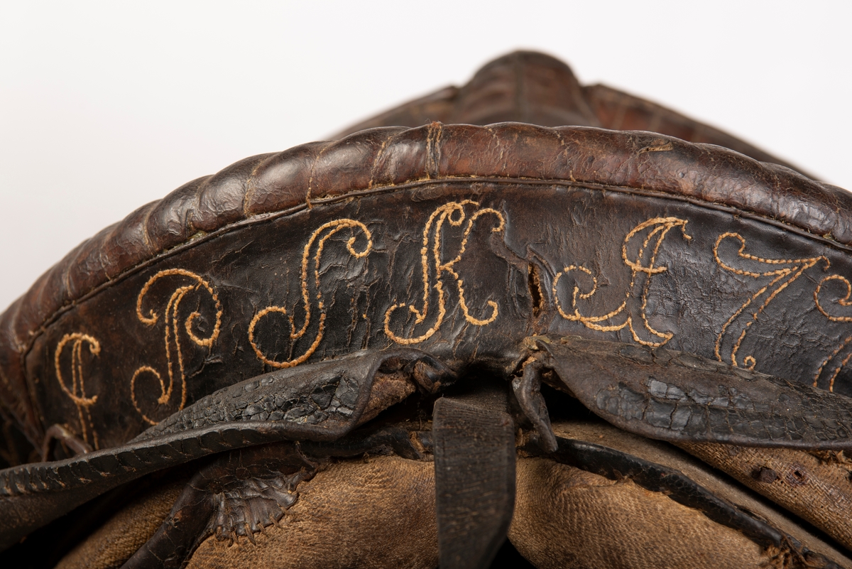 Heltrukket med lær. Initialene, antatt, JPSK og årstallet 1772 brodert på læret. 2 stigbøyler av jern, 3 lærremmer, halerem og 1 gjord. 