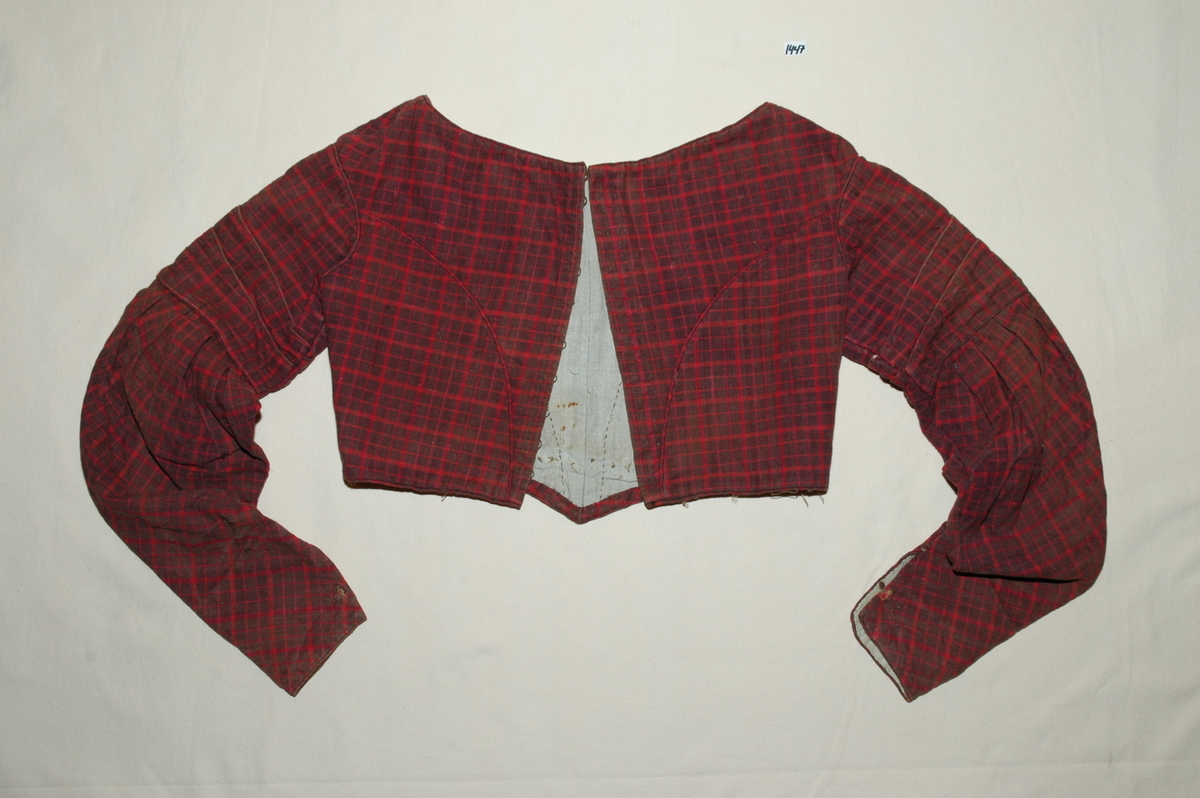 Kjoleliv av rutet bomullslerret med linfôr. Livet er håndsydd og stoffet er trolig hjemmevevd. Kjolelivet er baklukket med ti hekter og maljer. Ryggstykket har innsatt en tittekant av hovedstoffet som en figursøm. Fôret er helt. Sidesømmer av spilesøm, ellers attersting og faldesting. ERmene er satt i med åpne attersting. Sømmonnet er kastet over. Skinkeermer med tittekant i isyingssømmen, tre rader med tittekanter. Ensømserme med ni motfolder (2,5 cm breie). Sju cm bred ermesplitt som lukkes med hekter. Livet går ned i spiss midt framme. Tittekant midt framme og i en buesøm midt framme. Tittekanter langs nedrekant og halsringing. Halsringingen er oval og ermene er satt i langt utpå. (Fra registrering ved Bunad- og folkedraktrådet/Norsk institutt for bunad og folkedrakt v/Jon Fredrik Skauge, 2005, revidert v/Bjørn Sverre Hol Haugen, 2020.)