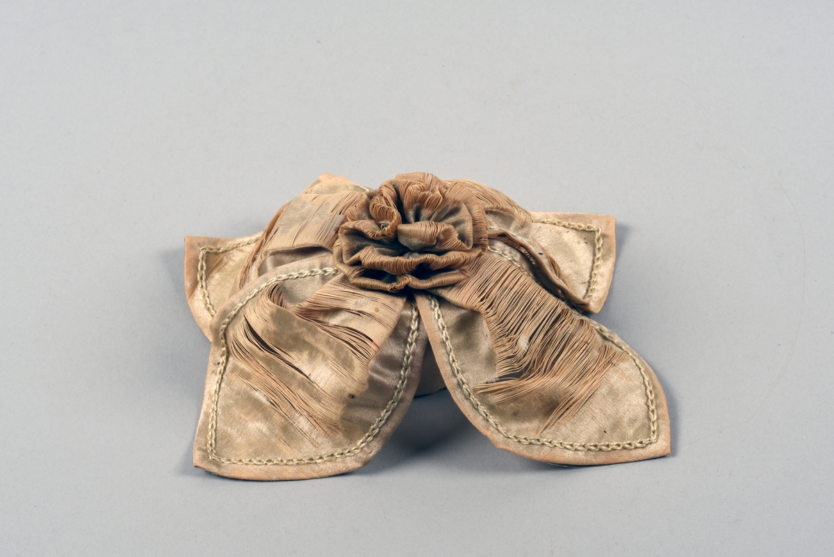 En av ett par fotogenlampor med gulmålad fot i plåt. På målningen finns tryckta stridsscener samt dekor med gotiska valv i svart. Foten är i form av en pelare på kvadratisk bas. Fotogenbehållaren är av glas och brännaren av mässing. Lampkupan är av opalfärgat glas med inslipad blomsterdekor. Högst upp ett skydd sytt i cremefärgat sidentyg, i form av en blomma.