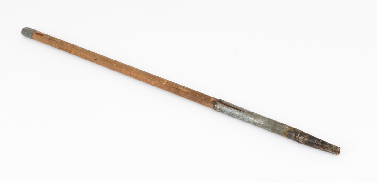Ladestav, brukt i forbindelse med grøftesprening i skog og utmark, der man forsøkte å drenere vekk vann som virket veksthemmende på produksjonsskogen. Dette redskapet er 109,5 centimeter langt og består av en rett trestav med ovalt tverrsnitt, samt et 36 centimeter høyt sinkgalvanisert endebeslag, ei slags hylse, som omslutter den ene enden av staven. Ettersom denne delen av staven er litt kon, ser det ut til at beslaget egentlig er lagd av to komponenter med litt ulike diametere, Den øverste delen av beslaget har dessuten to sidespalter, som nok er en tilpasning til stavens noe økende tjukkelse fra ytterenden og oppover. Beslaget er forankret i trestaven ved hjelp av to gjennomgående nagler. Rundt den øvre enden av treskaftet er det viklet litt grå tape.