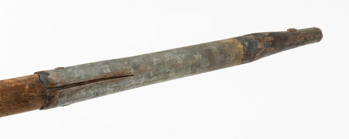 Ladestav, brukt i forbindelse med grøftesprening i skog og utmark, der man forsøkte å drenere vekk vann som virket veksthemmende på produksjonsskogen. Dette redskapet er 109,5 centimeter langt og består av en rett trestav med ovalt tverrsnitt, samt et 36 centimeter høyt sinkgalvanisert endebeslag, ei slags hylse, som omslutter den ene enden av staven. Ettersom denne delen av staven er litt kon, ser det ut til at beslaget egentlig er lagd av to komponenter med litt ulike diametere, Den øverste delen av beslaget har dessuten to sidespalter, som nok er en tilpasning til stavens noe økende tjukkelse fra ytterenden og oppover. Beslaget er forankret i trestaven ved hjelp av to gjennomgående nagler. Rundt den øvre enden av treskaftet er det viklet litt grå tape.