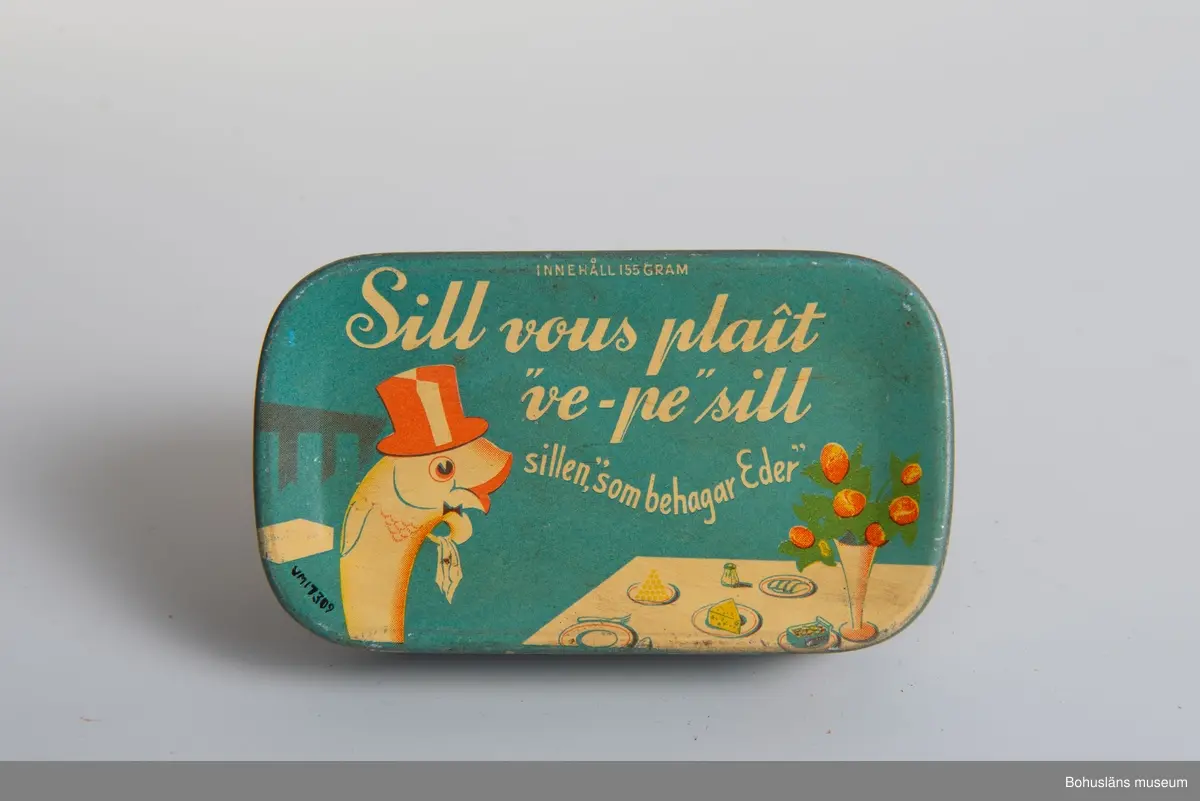 Rektangulär blå burk, vit text. På lock, botten och sidor: "Sill vous plait "ve-pe" sill, sillen, "som behagar Eder" i botten även "Innehåll
155 gram." På sidan: Luckeys, A-B. Elis Luckeys Konservfabrik Lysekil,
Sweden" och engelsk innehållsdeklaration.
Se även UM17232.