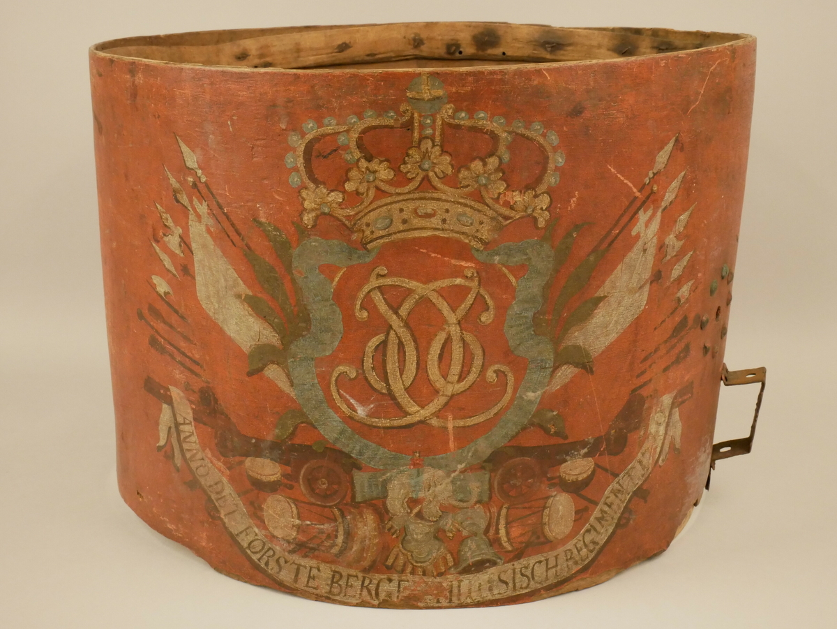Måla dekor på utsida, sentrisk likt på kvar side av midtakse. I senter truleg riksvåpen med Christian 6. sitt monogram og krune øvst. Spyd og økser på kvar side. Ulike typar trommer nedst saman med kanoner og anna militært utstyr. Skrift heilt nedst.